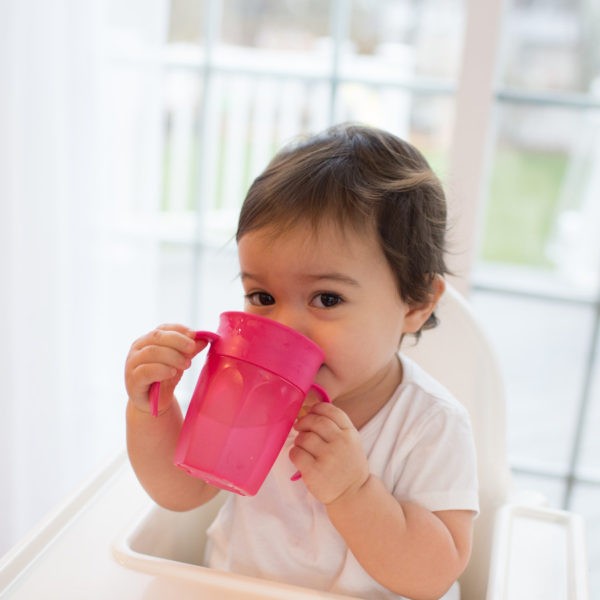 Baby sitting in highchair drinking from cheers360