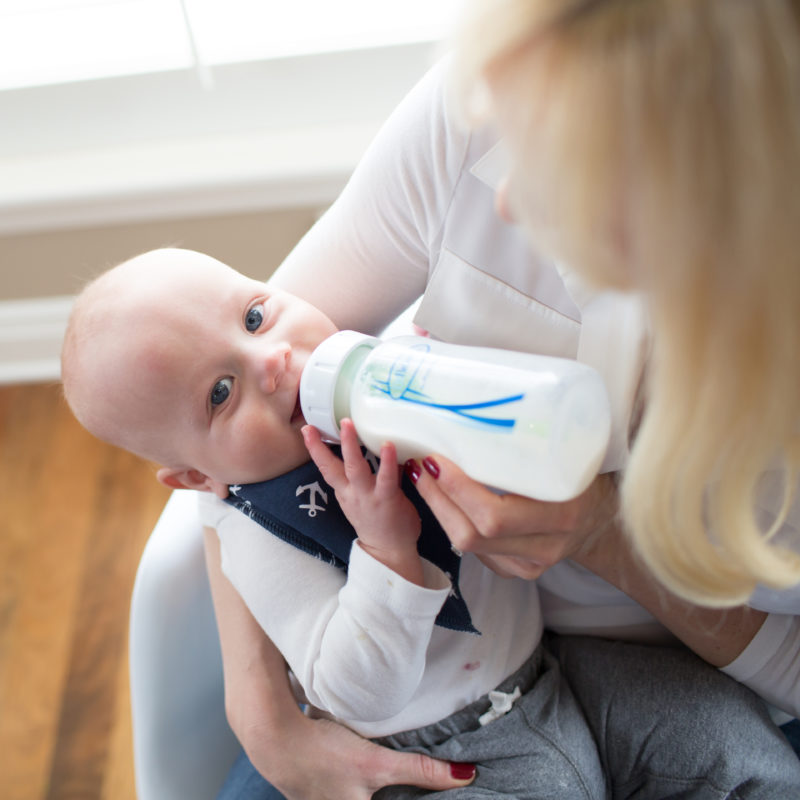 women holding baby and feeding with baby bottle