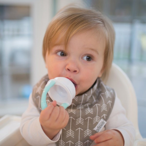 Baby sitting in highchair eating from silicone feeder